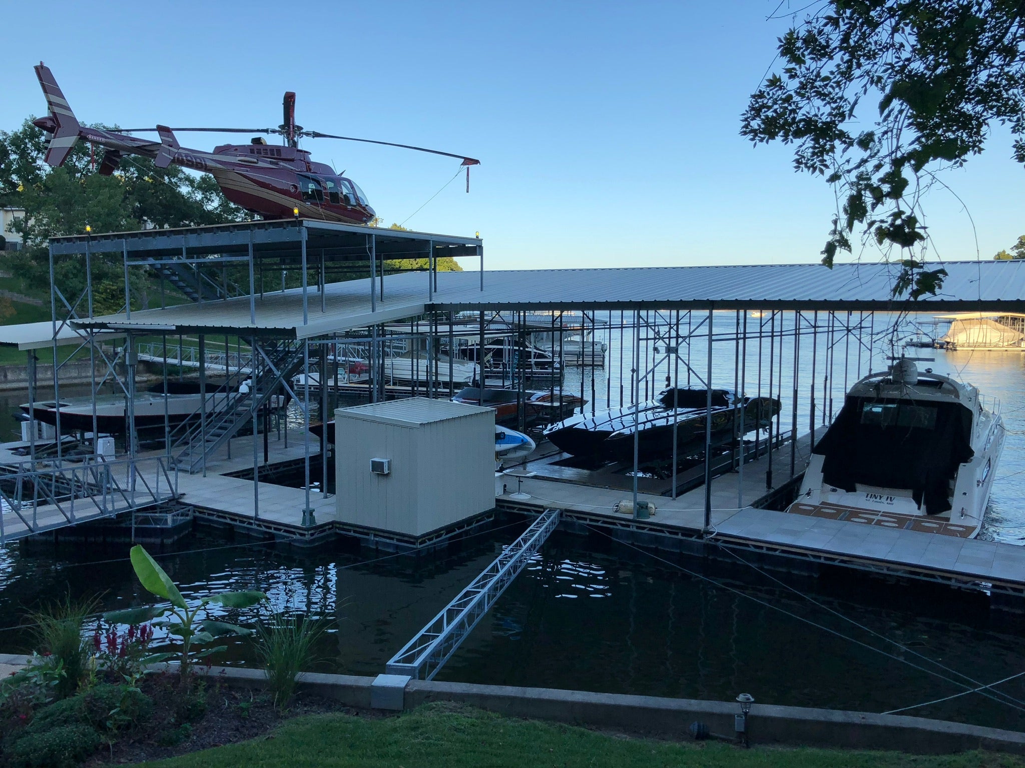 Photo of a dock with two boats docked and a helicopter on the roof