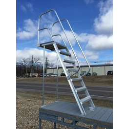 The Polylift WetStep High Dive features a sturdy aluminum stairway with handrails on both sides, leading to a compact outdoor platform situated near a road and in front of a building under partly cloudy skies.